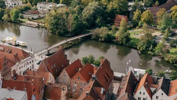 Roofs with red tiles, bridge over quiet river.