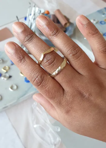 A hand with two rings surrounded by jewelry accessories.