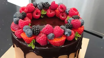 Schokoladentorte mit Beeren und grüner Dekoration.