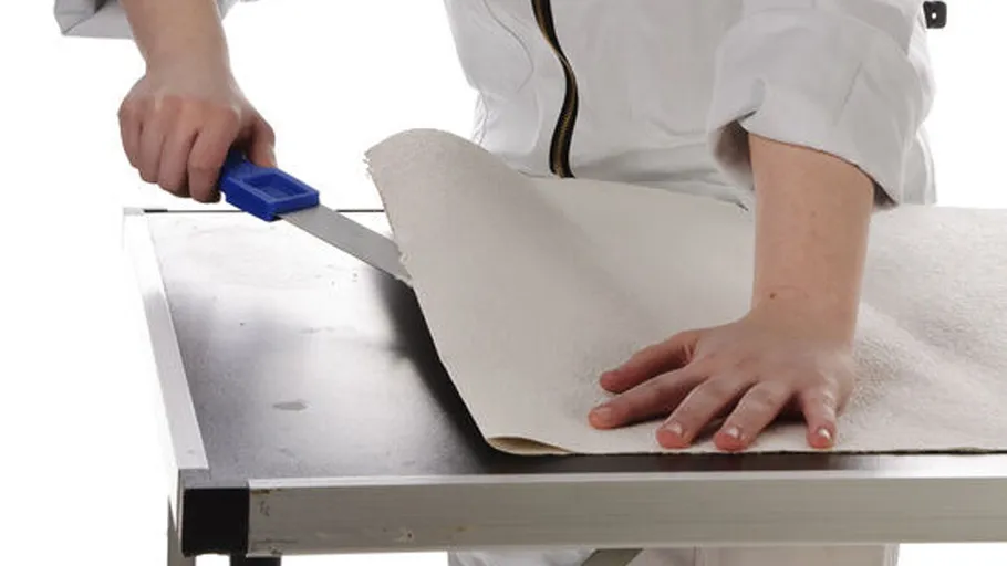 A hand cuts a piece of paper with a knife.