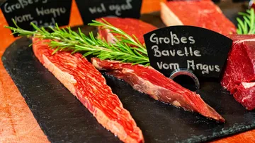 Red meat is on a bulletin board with rosemary.