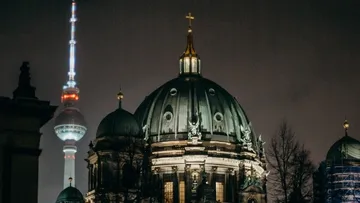 Berliner Dom leuchtet nachts, Fernsehturm im Hintergrund sichtbar.