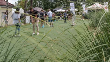 People putt on a golf course at an event.