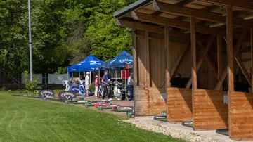 Golfers practice on a driving range with stands.