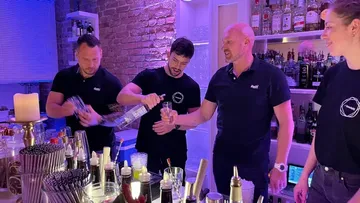 Bartender pours drinks into glasses behind the bar.
