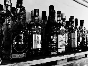 Shelf with various spirits, presented in a black and white setting.