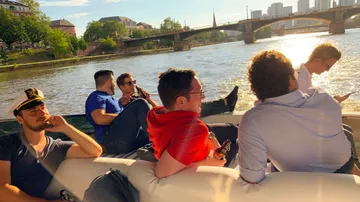 Gruppe von Personen entspannt auf einem Boot am Fluss.