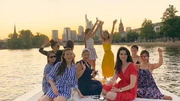Gruppe von Frauen feiert auf einem Boot bei Sonnenuntergang.
