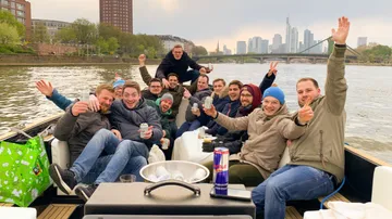 Group of men partying on a boat by the river.