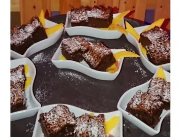 Delicious brownies on plates with fresh mango pieces.