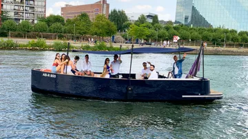 A boat with people sails on a body of water.