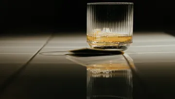 Ein Glas mit Whisky steht auf dem Tisch.