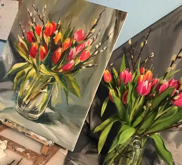Vase with colorful tulips and paintings in the background.