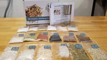 Spices and salts are presented on a wooden table.