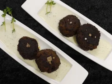 Frittierte Laibchen auf weißer Sauce mit Kräutern.