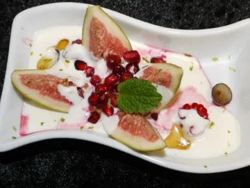 Eine Schüssel enthält Feigen, Granatapfelkerne und Joghurt.