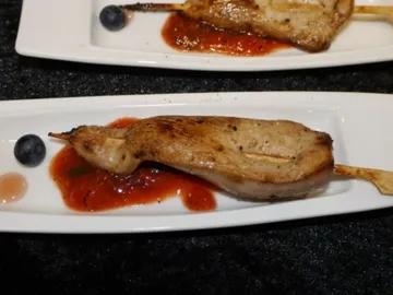 Gegrilltes Fleisch auf einem Teller mit Sauce und Obst.