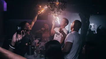 People party with sparks over a table in a nightclub.