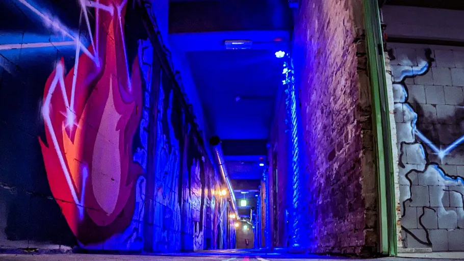 Dunkler Flur mit bunten Graffiti und schwachem Licht.