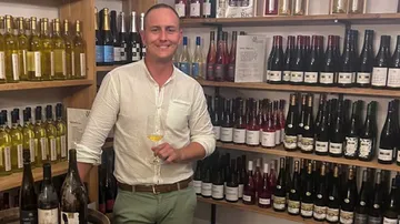 Ein Mann hält ein Weinglas in einem Weinladen.