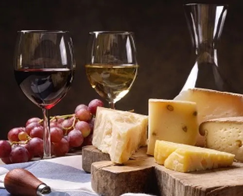 Cheese plates with wine and grapes on a wooden board.