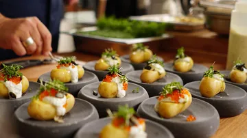 Small potatoes with garnish are served on plates.