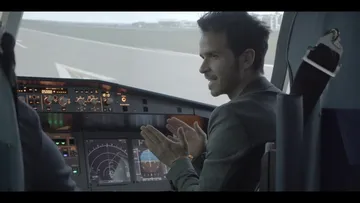 Pilot im Cockpit erklärt Steuerungen in Flugzeugsimulator.