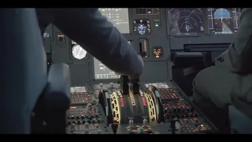 Ein Pilot steuert das Cockpit mit verschiedenen Instrumenten.