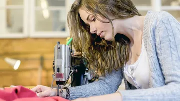 Woman is concentrating on a sewing machine in a workshop.