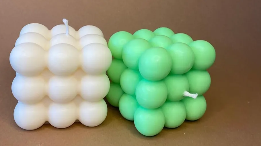 Weiße und grüne Kerzen in quadratischer Form stehen nebeneinander.
