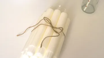 Five white candles are tied with string.