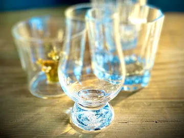 Glasses are on a wooden table, sun shines on them.