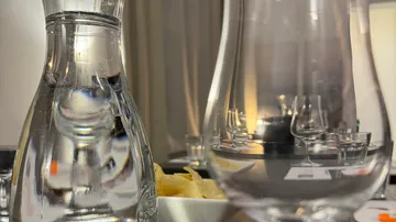Glasflasche und Glas reflektieren Licht auf einem Tisch.