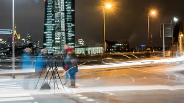 The stand is standing, people move around the city at night.