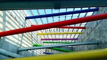 Colourful pipes hang diagonally in a light-flooded room.