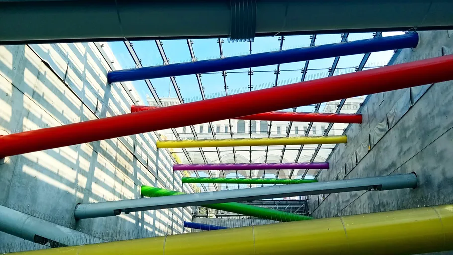 Colourful pipes hang diagonally in a light-flooded room.
