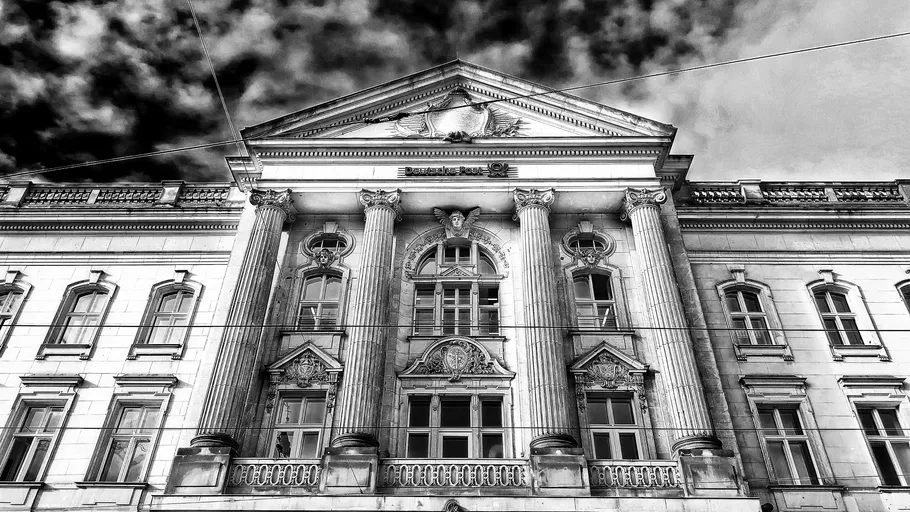 Historic building with columns, under cloudy sky.