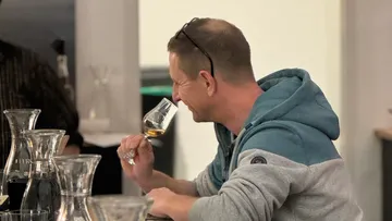 Man smells a glass of whiskey in a bar.