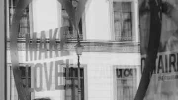 Shop window reflection with 'MAKE LOVE' text.