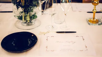 Table setting decorated with glasses, cutlery and flower vase.