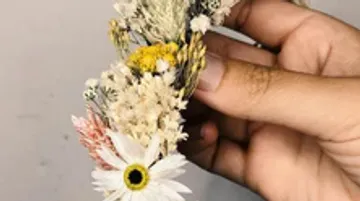 Blumenkranz wird von einer Hand gehalten, dekorativ gestaltet.