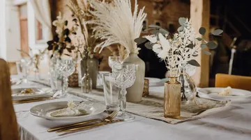 Eleganter Tisch dekoriert mit Blumen und Glaskerzen.
