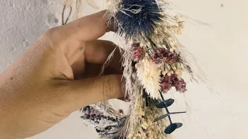 Getrocknete Blumen werden von einer Hand gehalten.