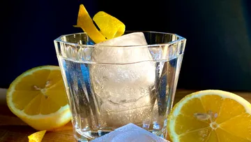 Ein Glas mit Eis und Zitronenscheiben auf Holzuntergrund.