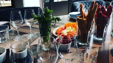 Tisch mit Gläsern, frischen Kräutern und fruchtigen Snacks.