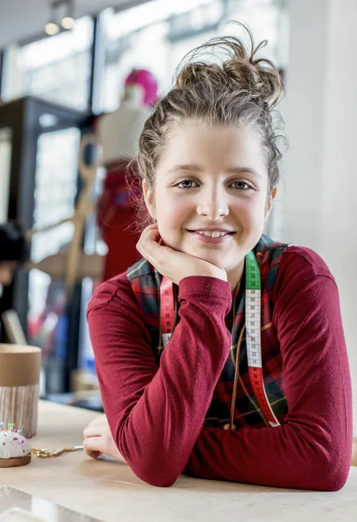 Mädchen lächelt, während sie auf einem Tisch sitzt.