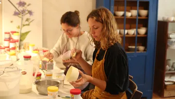 Two women create cups in a bright studio.