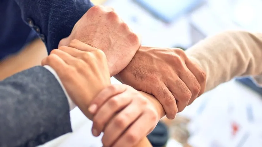 Hände greifen einander in einem Team- oder Zusammenarbeitskontext.