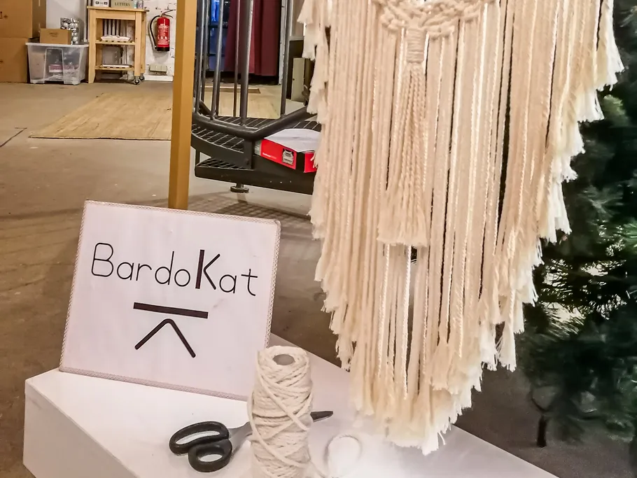 Makramee-Wandbehang hängt, Material und Werkzeuge daneben.