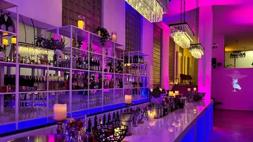 Moderne Bar mit bunten Lichtern, zahlreiche Getränke stehen bereit.